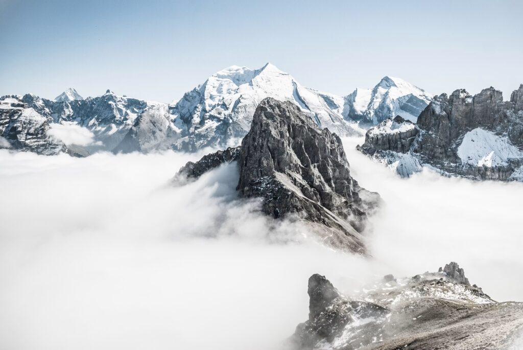 Verschneite Berggipfel ueber einer geschlossenen Nebeldecke